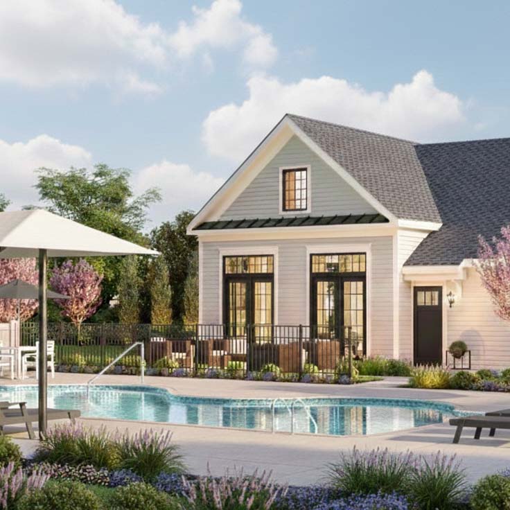 A bright, daylight view of the resort-style swimming pool and clubhouse at Regency at West Windsor, a 55+ community in NJ, featuring black lounge chairs, lush green trees, and a clear sky with light clouds.